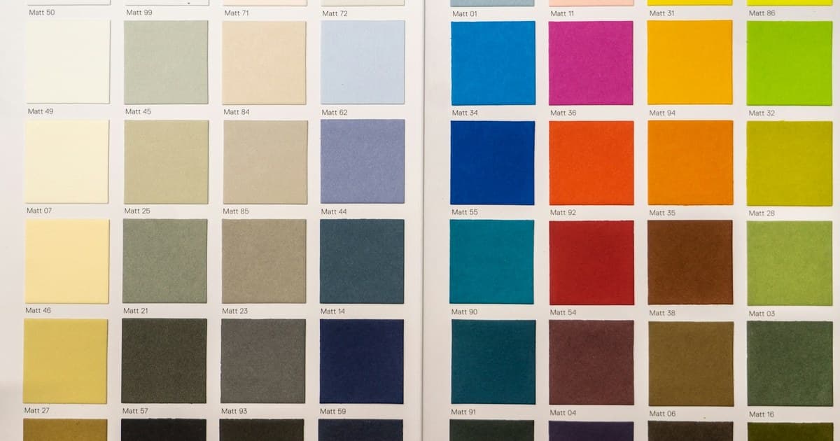 Mostre de hârtie colorată, în nuanțe deschise și intense, într-un catalog de culori.